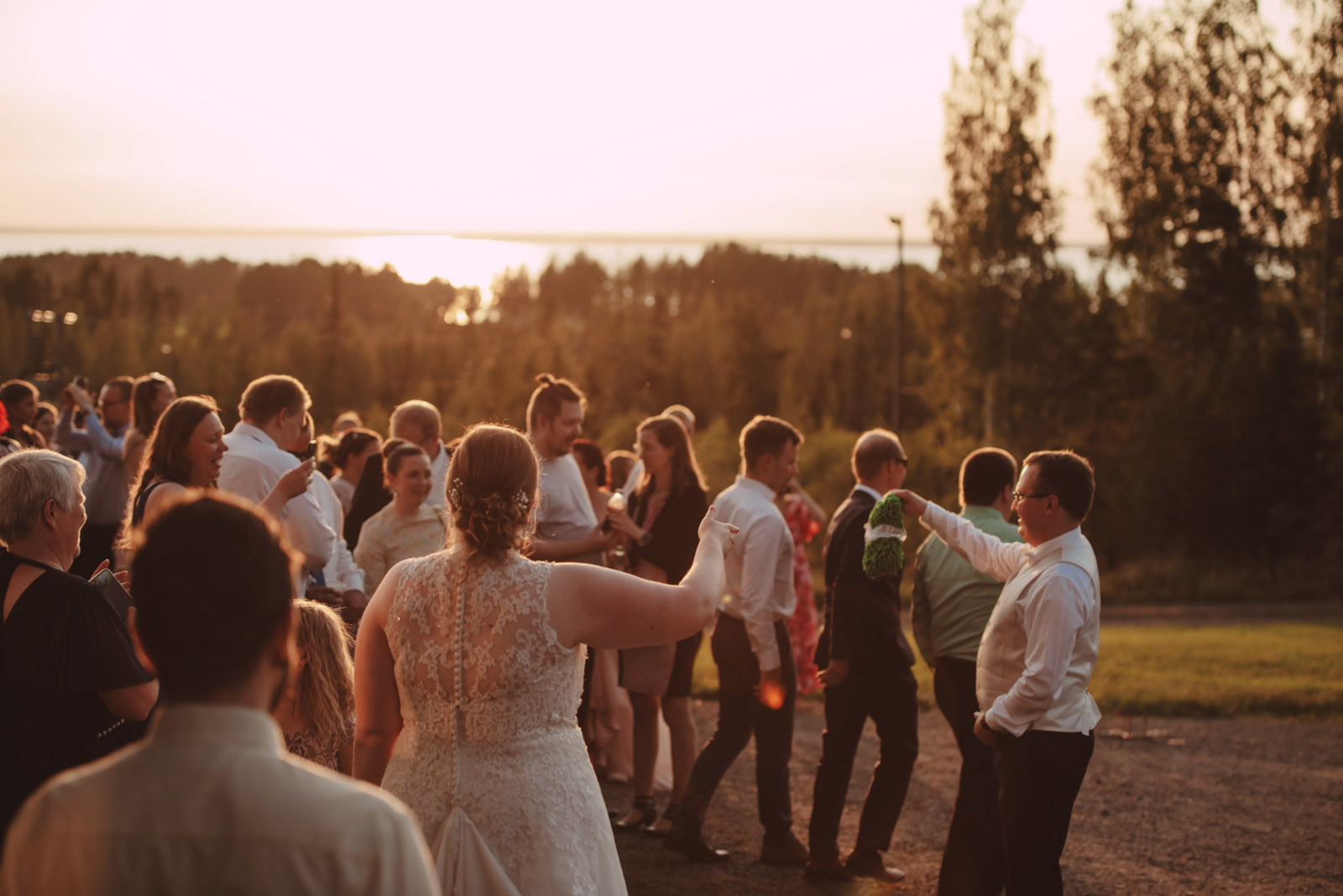 Häiden vieraat juhlatunnelmissa kauniissa auringnlaskumaisemassa.